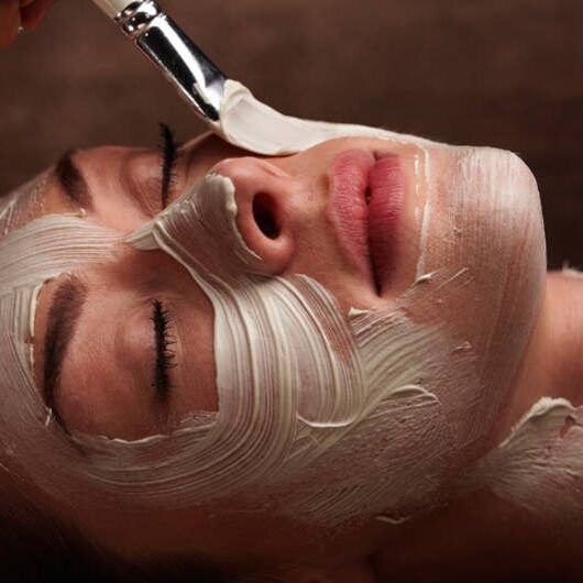 A cream facial mask being applied with a brush